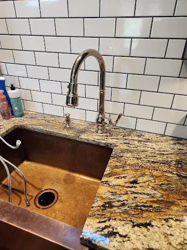 Polished gooseneck kitchen faucet installed over a copper undermount sink