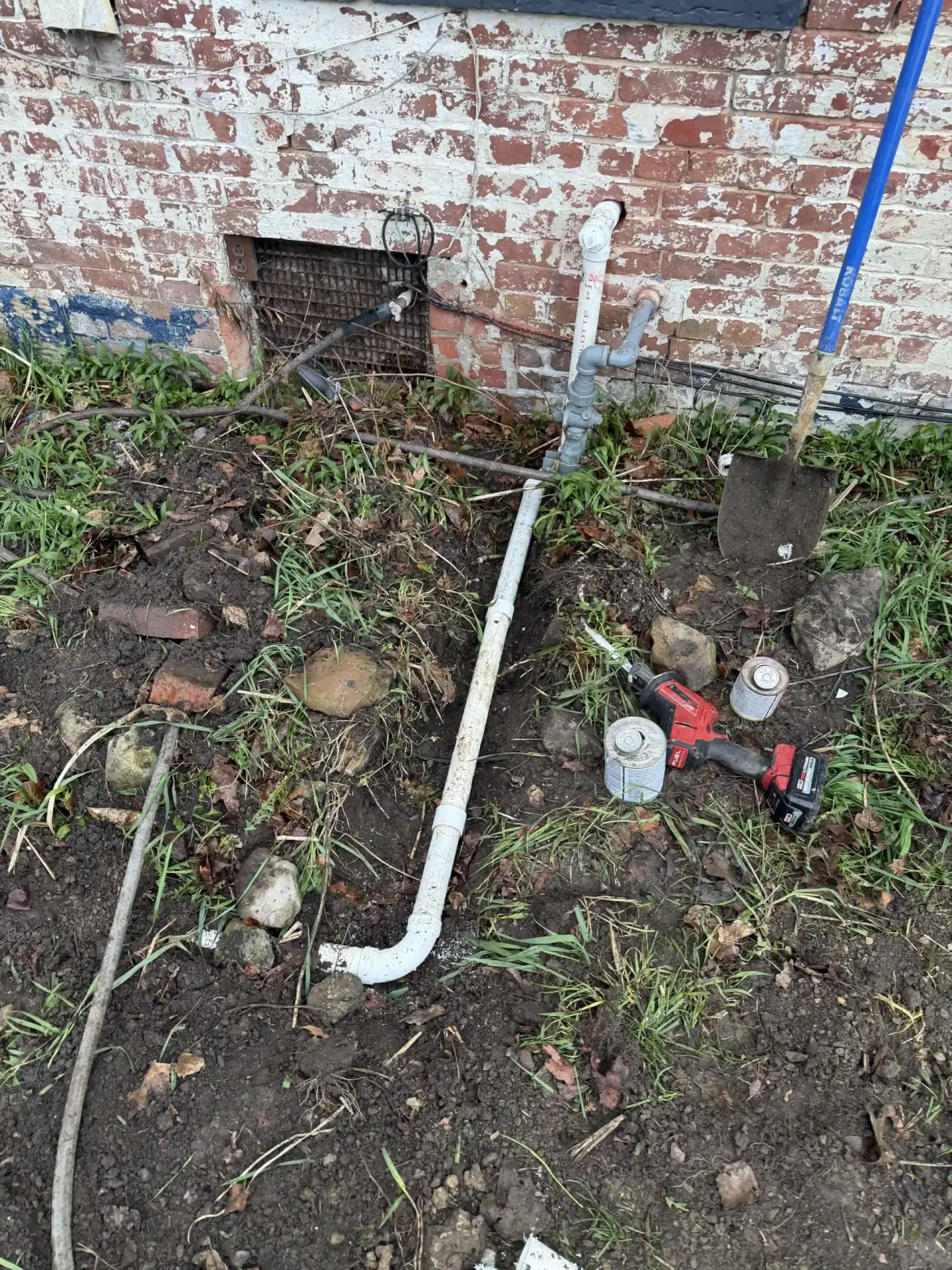 PVC pipe repair along a home's foundation with excavation and tools
