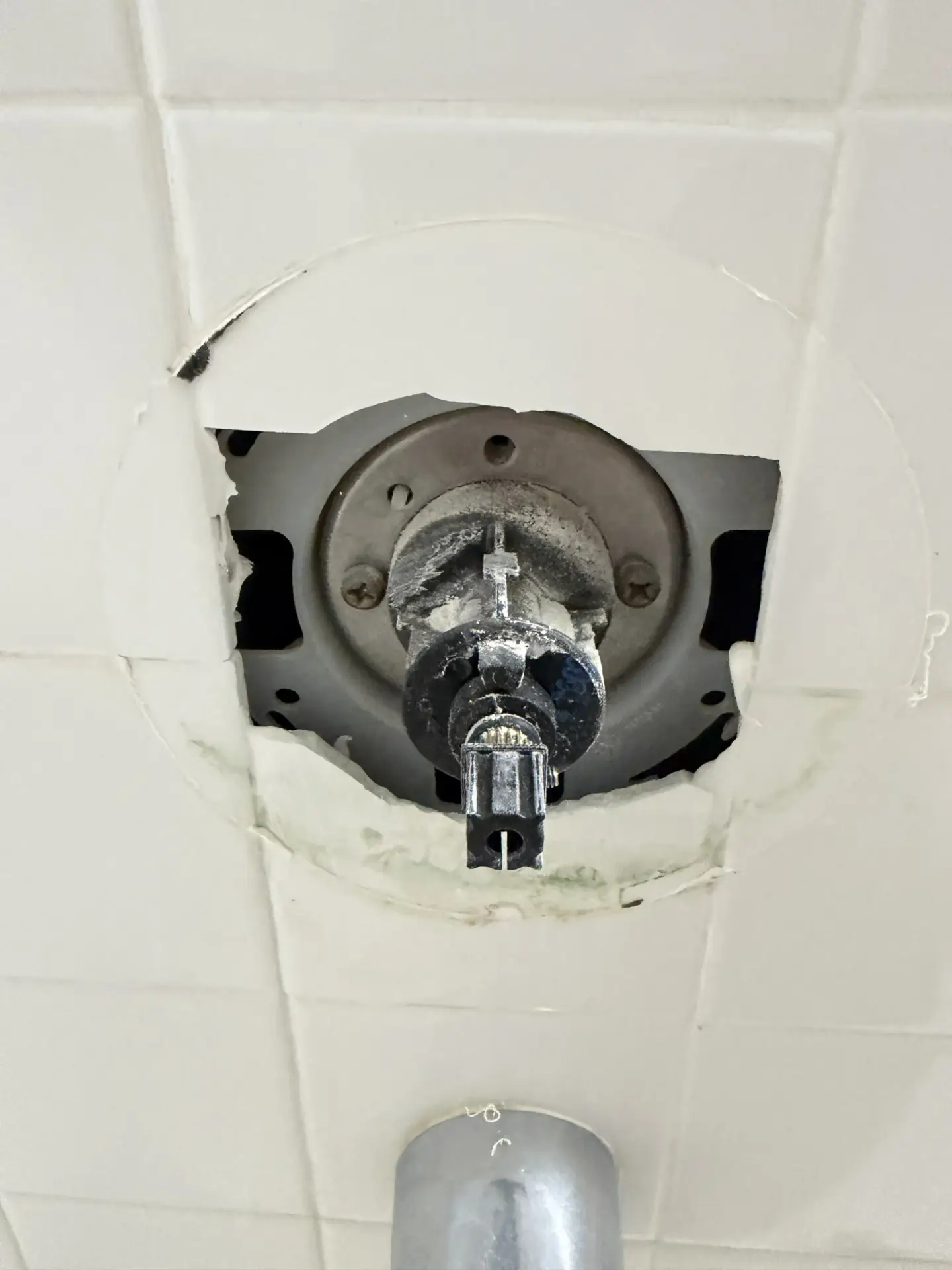 Shower valve rough-in exposed in a tiled shower wall