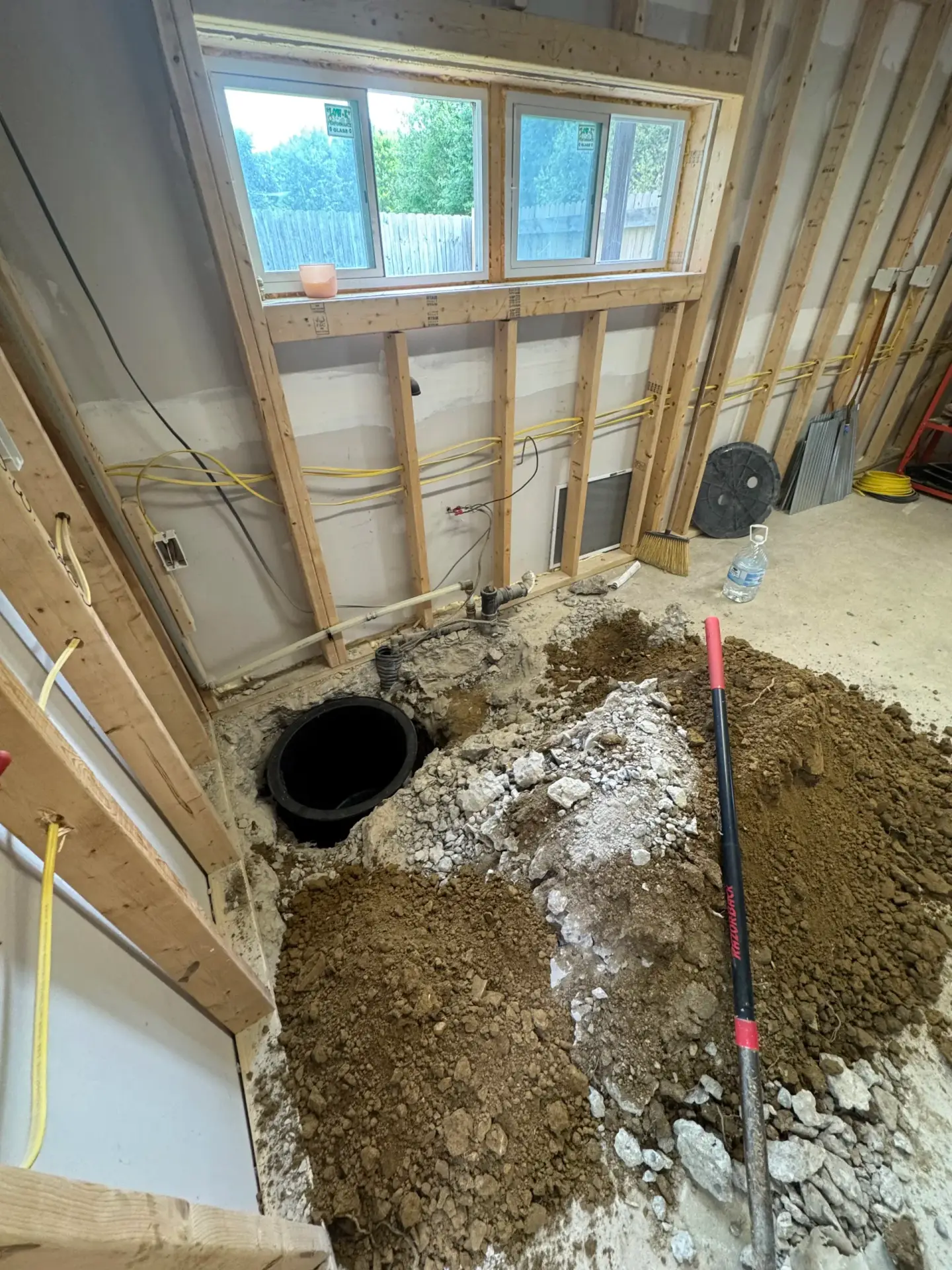 New bathroom floor rough-in with plumbing basin exposed during construction