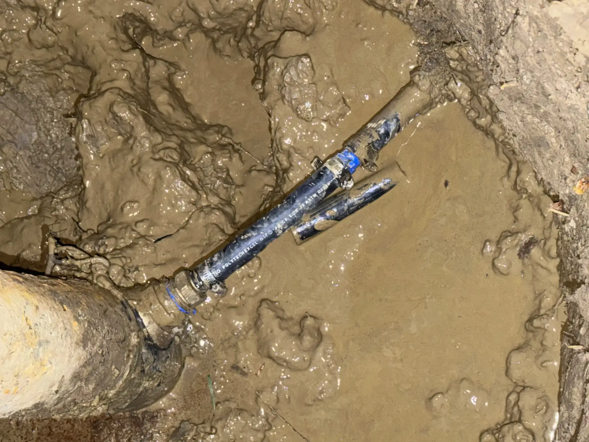 Underground water line repaired with a new coupling in an excavated trench
