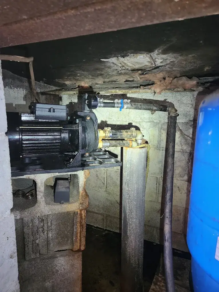 Well pump and pressure tank system installed in a home's crawlspace